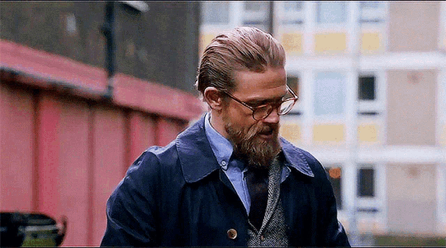 a man with a beard wearing glasses and a coat