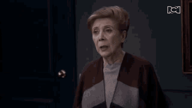 an older woman is standing in front of a door with the letters bc on the bottom
