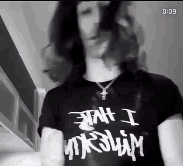 a man with long hair is wearing a black t-shirt that says " jah i mrslim "
