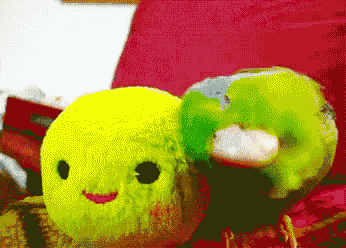 a yellow and green stuffed animal with a face on it