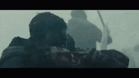 a man is carrying a dead man on a stretcher in a foggy scene .