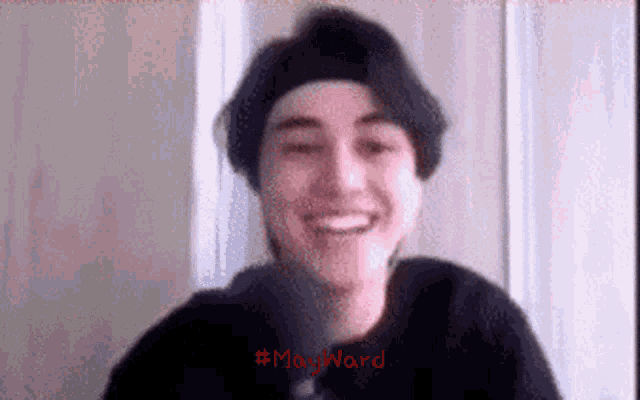 a man wearing a black hat is smiling in a video call .
