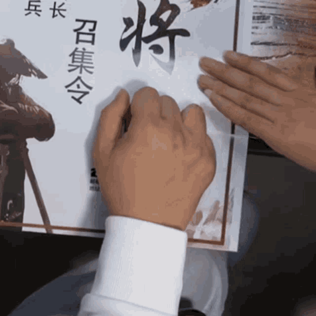 a person holding a piece of paper with chinese characters on it