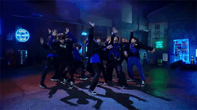 a group of young men are dancing on a street in front of a neon sign that says the notice .