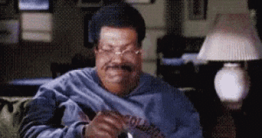 a man wearing glasses is sitting on a couch holding a piece of paper with the word college on it