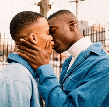 two men in blue jackets are kissing each other .