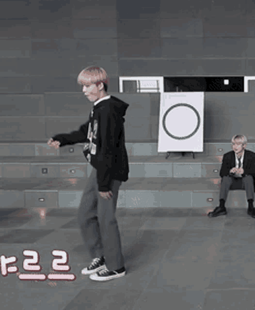a man in a black hoodie is dancing in front of a sign that says o on it