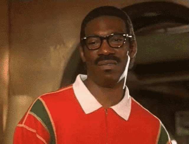 a man with glasses and a mustache is wearing a red and green striped shirt .