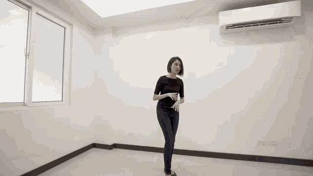 a woman is standing in an empty room with the words this townhouse is near greenhills shopping centre on the bottom