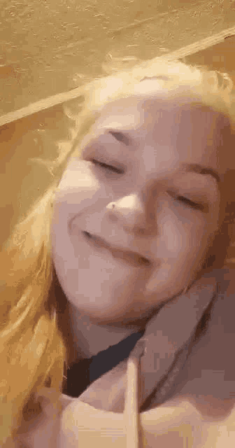 a close up of a woman making a funny face with her eyes closed and a nose ring .