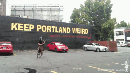 a man is riding a bike in front of a large sign that says keep portland weird