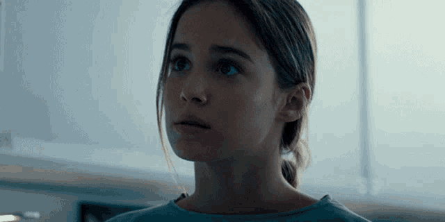 a close up of a girl 's face with a blue shirt on