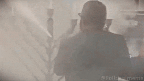 a man in a suit and tie is standing in a room covered in smoke .
