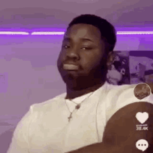 a man with a beard is wearing a white shirt and a necklace and making a funny face .