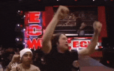 a man with his arms in the air in front of a sign that says ecw fc