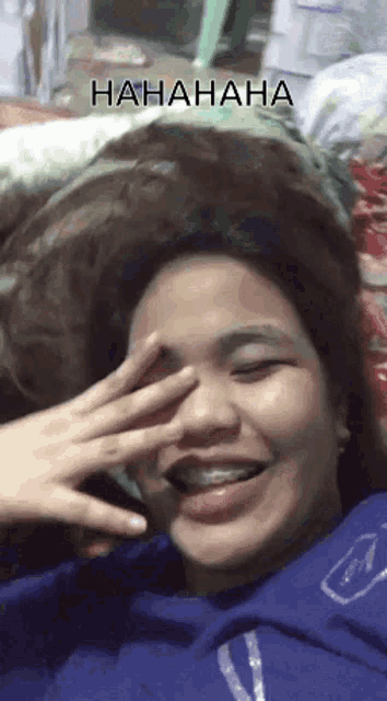 a woman with braces on her teeth is laughing and covering her eyes with her hand .