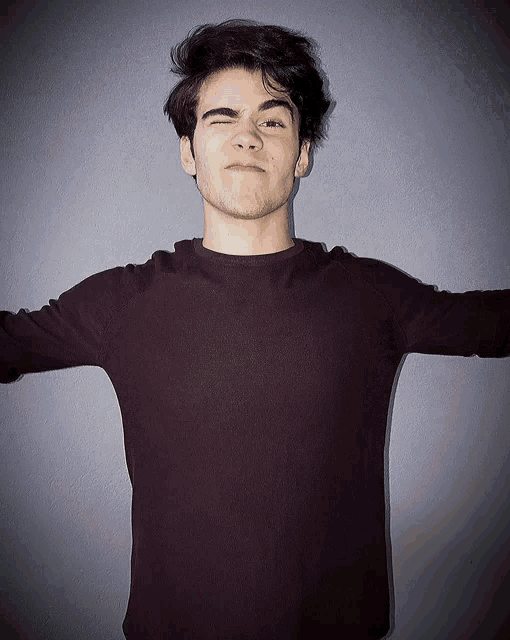 a young man with his arms outstretched making a face