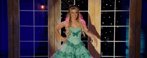 a woman in a green dress with a butterfly on it is standing in front of a window .