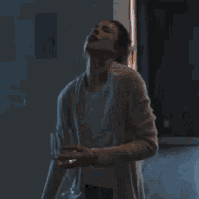 a woman is standing in a living room holding a glass of wine