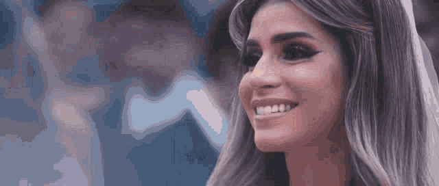 a close up of a woman 's face smiling with a blue background .