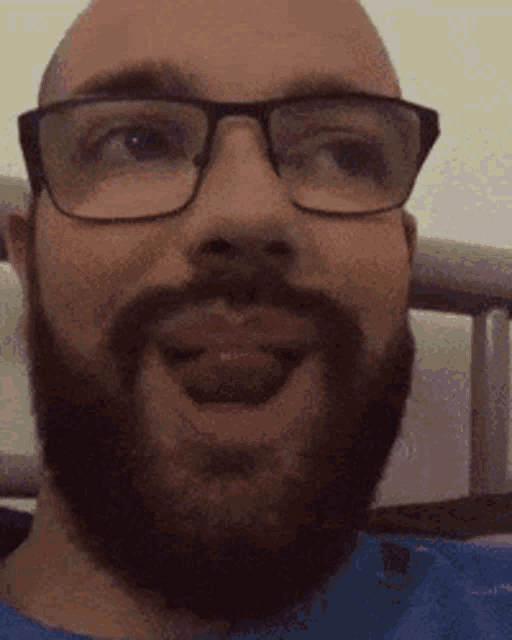 a man with glasses and a beard is sticking out his tongue .