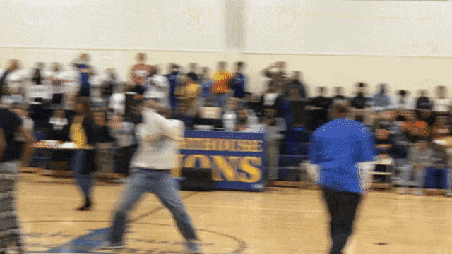 a blurry photo of people playing basketball in front of a banner that says lions