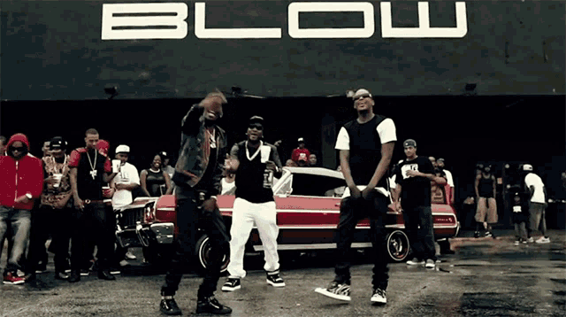 a group of men are dancing in front of a building that says blow