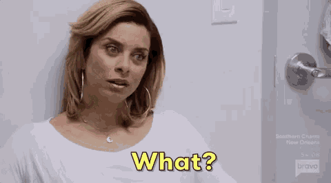 a woman in a white shirt is standing in front of a door and asking what .