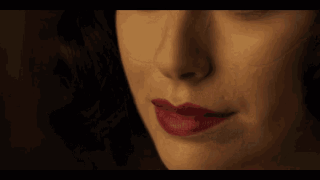 a close up of a woman 's face with green eyes and red lipstick .