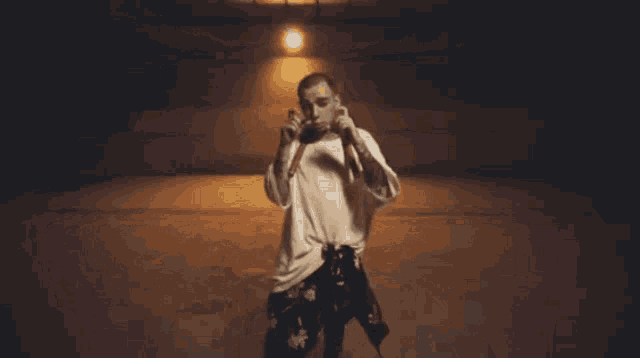 a man in a white shirt is standing in a dark room holding a microphone