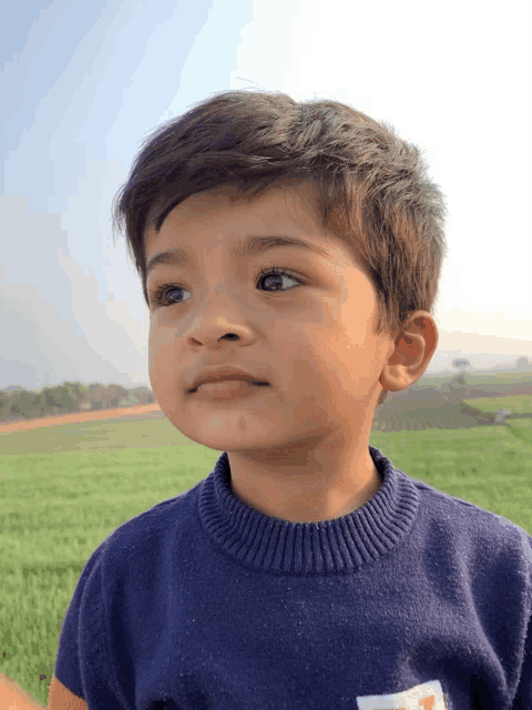 a young boy wearing a blue sweater with the letter t on his chest