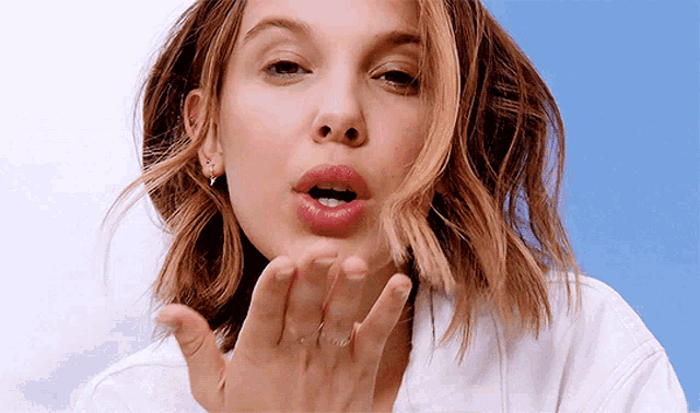 a young woman blowing a kiss with her hand