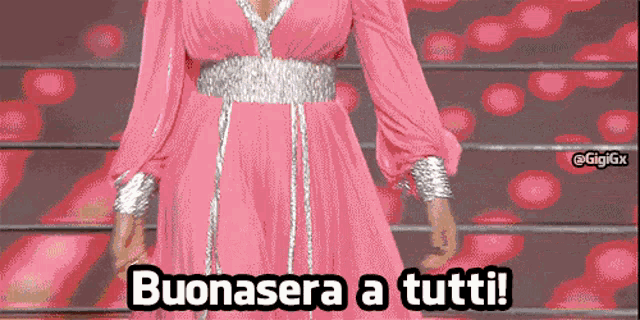 a woman in a pink dress with the words buonasera a tutti written below her