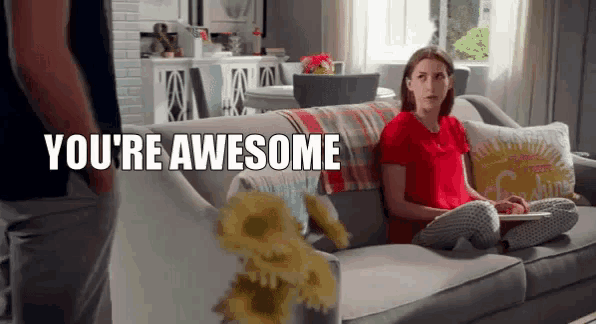a woman is sitting on a couch in a living room and a man is standing next to her .