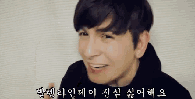a man in a black hoodie is making a funny face in a video .