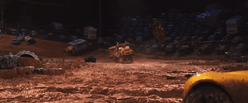 a yellow truck is driving through a muddy area with other cars