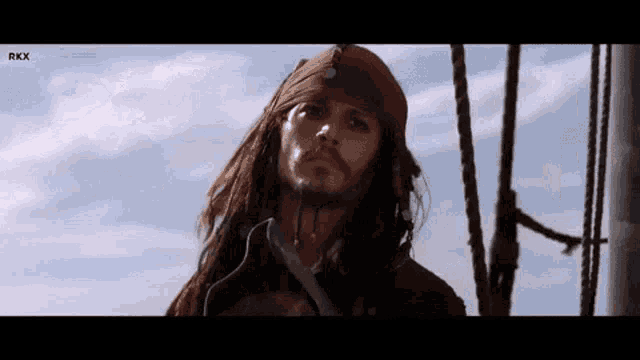 a man with dreadlocks and a bandana on his head is standing on a ship .