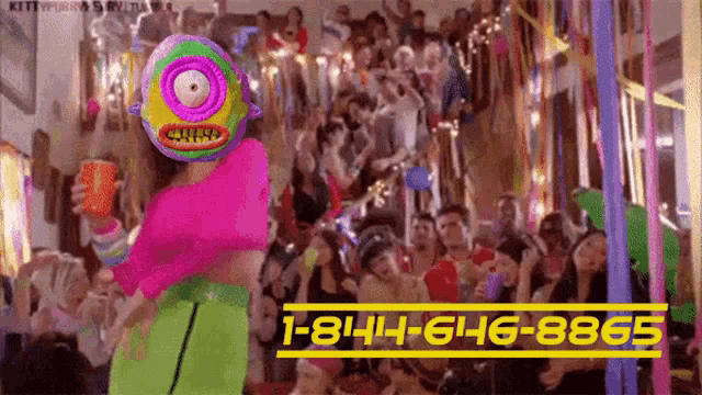 a woman with a colorful mask on her head is dancing in front of a crowd of people .