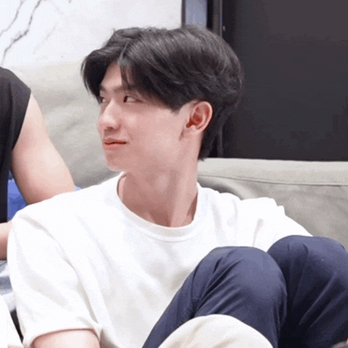 a young man in a white shirt is sitting on a couch