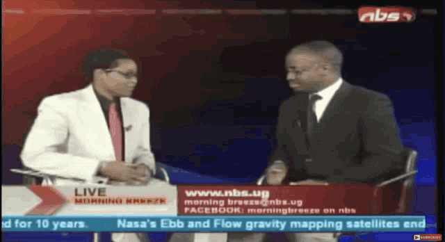 two men are sitting in front of a screen that says nbs on it