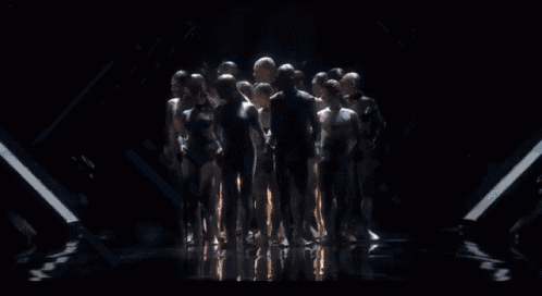 a group of people are standing in a dark room looking at each other