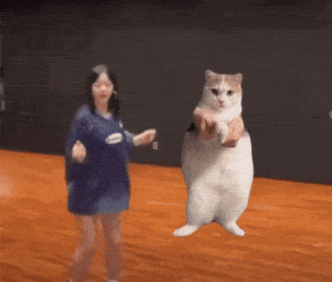 a woman in a blue shirt is dancing with a cat on her shoulder