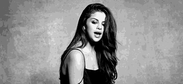a black and white photo of a woman in a black tank top .