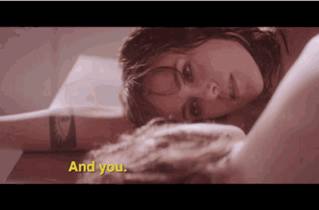 a close up of a woman laying on a bed with the words and you in yellow