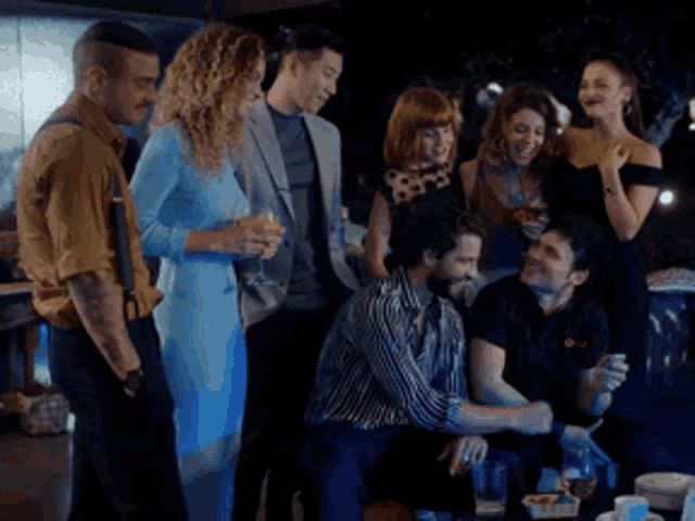 a group of people are gathered around a table with drinks and food