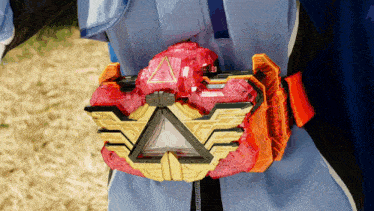 a person wearing a blue jacket has a red and gold item on their waist