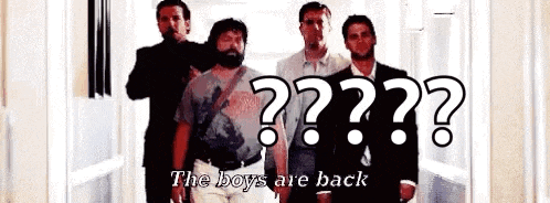 a group of men are standing next to each other in a hallway with a sign that says `` the boys are back '' .
