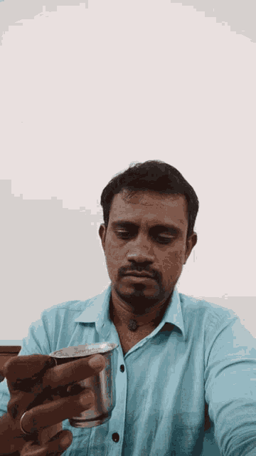 a man in a blue shirt is holding a silver cup in his hand
