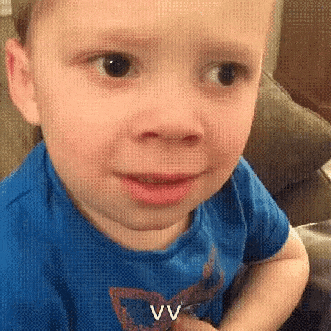 a little boy is making a funny face while sitting on a couch .