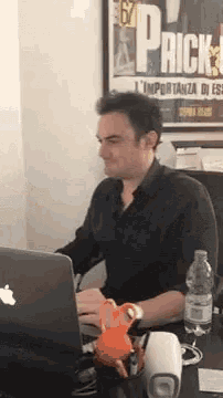 a man is sitting at a desk with a laptop and a bottle of water